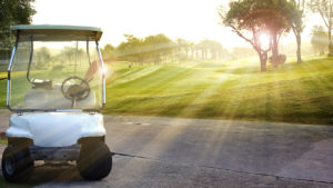 A GOLF CART PARKED IN FRONT OF A SUNNY GOLF COURSE