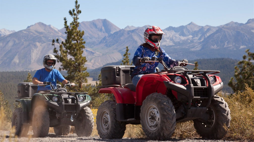 TWO PEOPLE ON ATV RIDING IN FRONT OF MOUNTAINS
